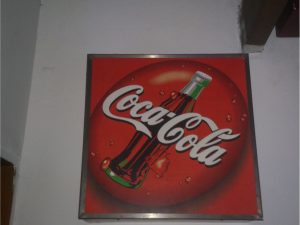 Display – Coca-Cola – Painel de aço inox escovado com acrílico e iluminação fluorescente.